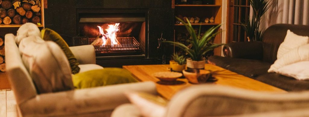 Salon chaleureux avec un canapé, des fauteuils et une cheminée allumée. Décoration accueillante.