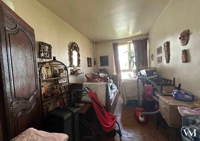 Chambre en désordre avec des meubles anciens et des décorations murales.