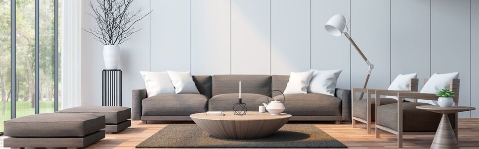 Salon moderne avec canapé gris, table basse ronde et lampadaire, lumière naturelle.