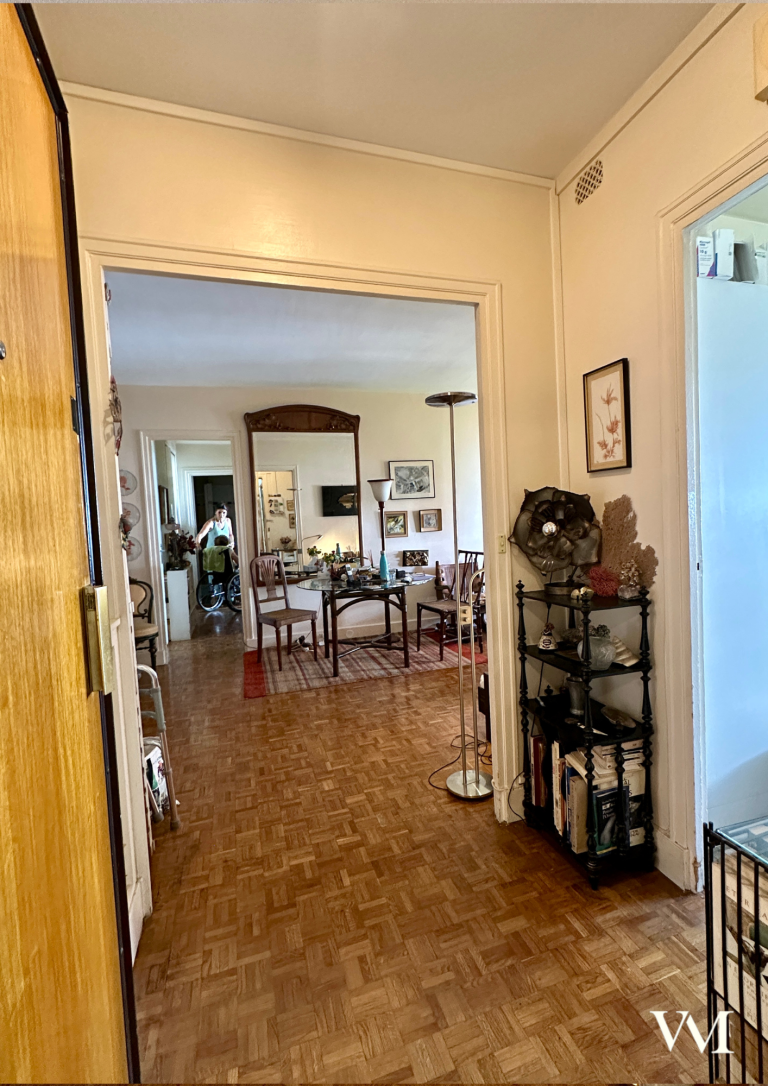 Vue d'un couloir menant à un salon avec mobilier et décoration élégante.