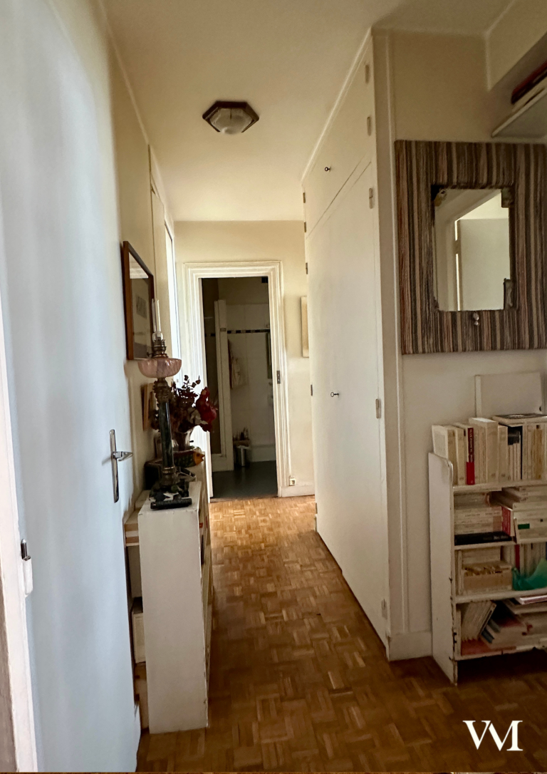 Un couloir lumineux avec des murs clairs et des meubles de rangement.