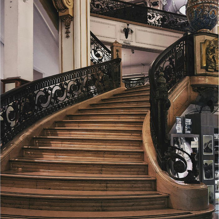 Viager Montaigne – Rester chez soi, l’esprit tranquille Escalier en bois avec rampes en métal décoratif dans un bâtiment élégant.