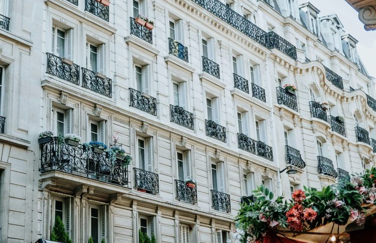 Viager occupé : 7 questions essentielles des propriétaires Façade d'un immeuble parisien avec balcons fleuris et détails architecturaux élégants.