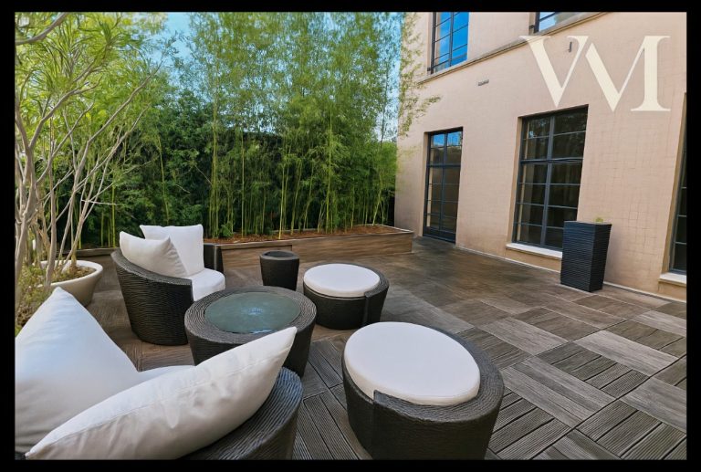 Espace extérieur avec canapés et tables, entouré de verdure.