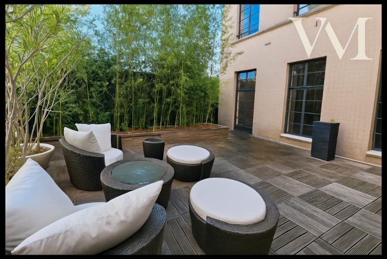 Espace extérieur avec canapés et tables, entouré de verdure.