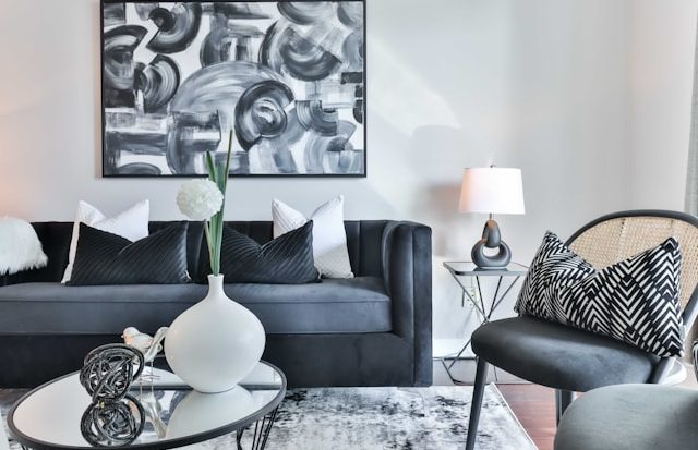 Viager occupé : 7 questions essentielles des propriétaires Salon moderne avec canapé noir, coussins blancs, table basse et œuvre d'art en noir et blanc.